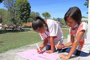 Children writing on a piece of paper.