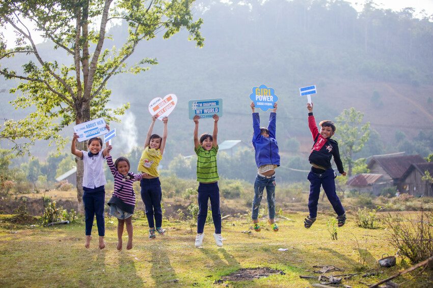 Children jumping holding signs.