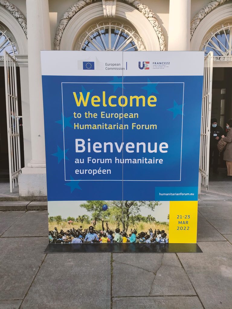 Sign at the entrance of the venue, with the caption "Welcome to the European Humanitarian Forum" in English and in French.