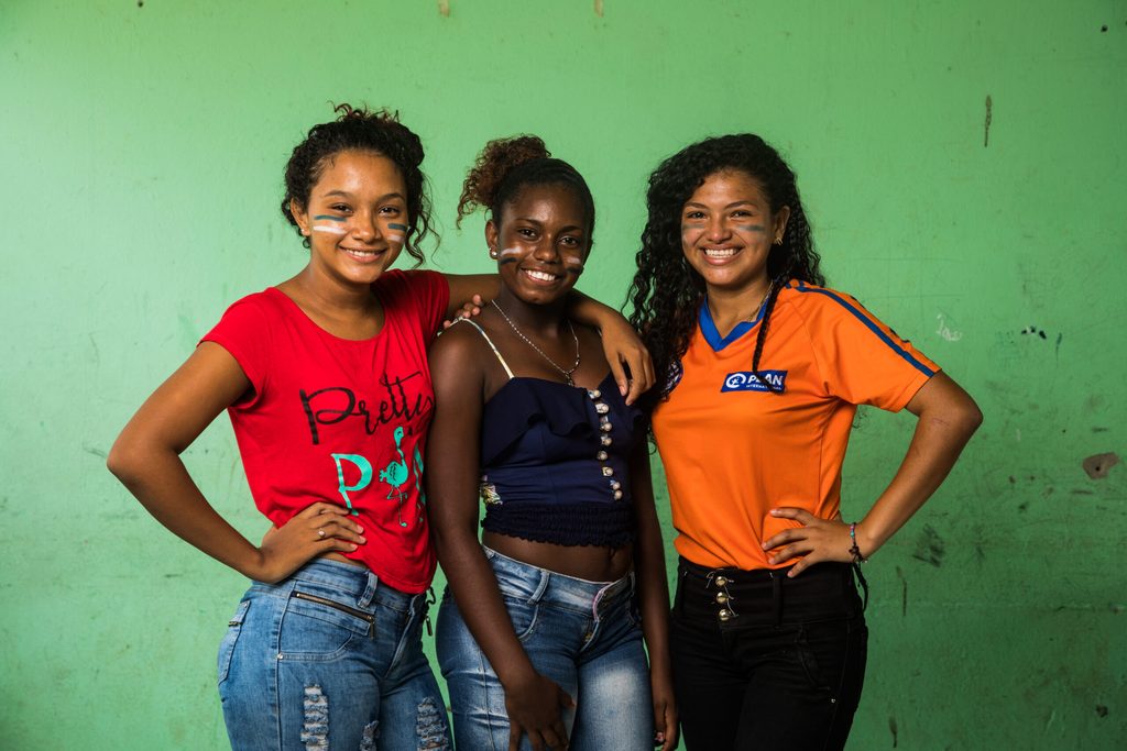 Three adolescent girls posing and smiling for the camera confidently.