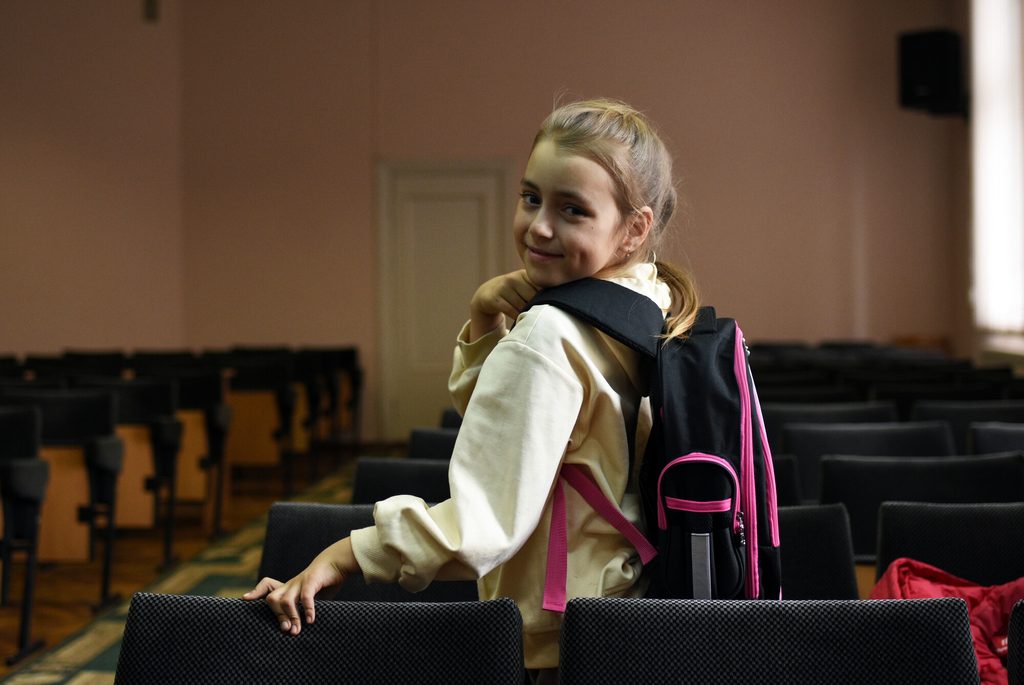 Girl wearing a school bag posing for the camera in her classroom in Moldova. 