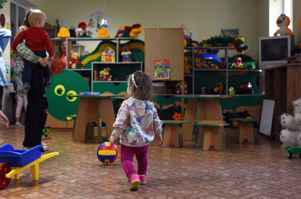 Toddler walking in a playroom in a classroom in Moldova.