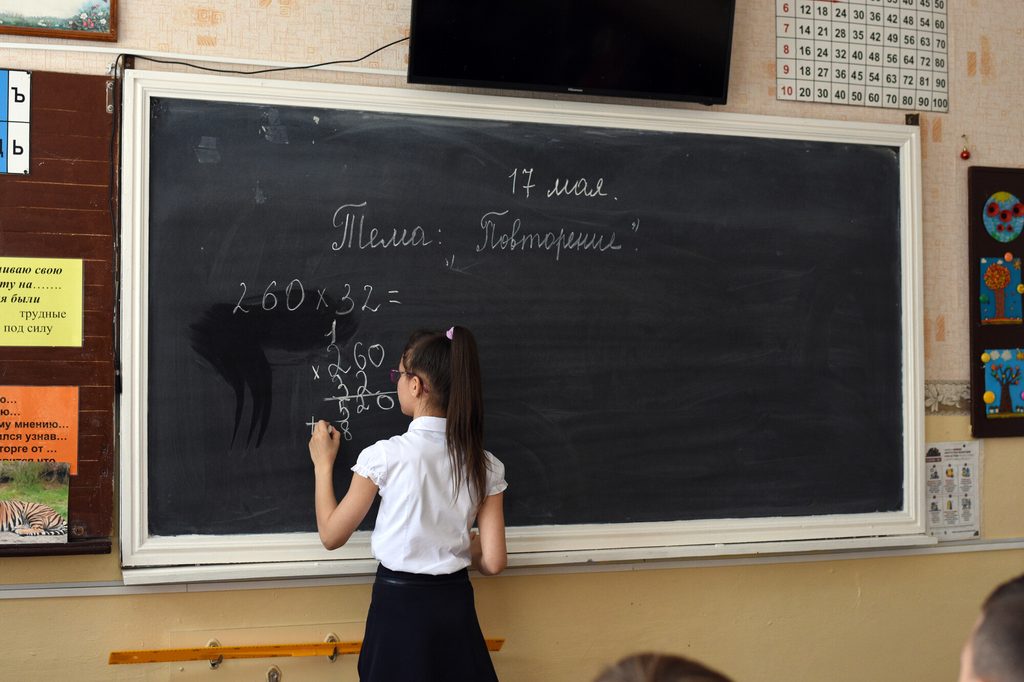 Girl writing on black board in her classroom in Moldova.