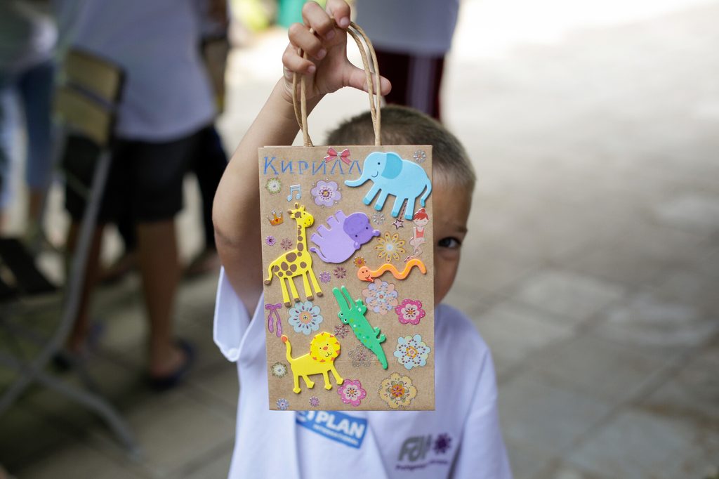 Young boy showing an "arts and crafts" decorated bag in Romania.