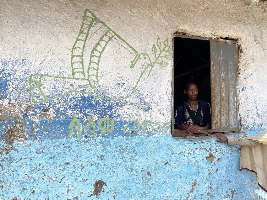 Girl looks through window at IDP camp set up in school in Amhara region.