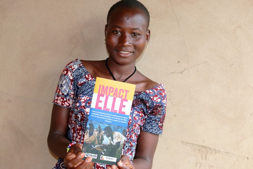 Karimatou holds up the Impact-Elle project handbook.