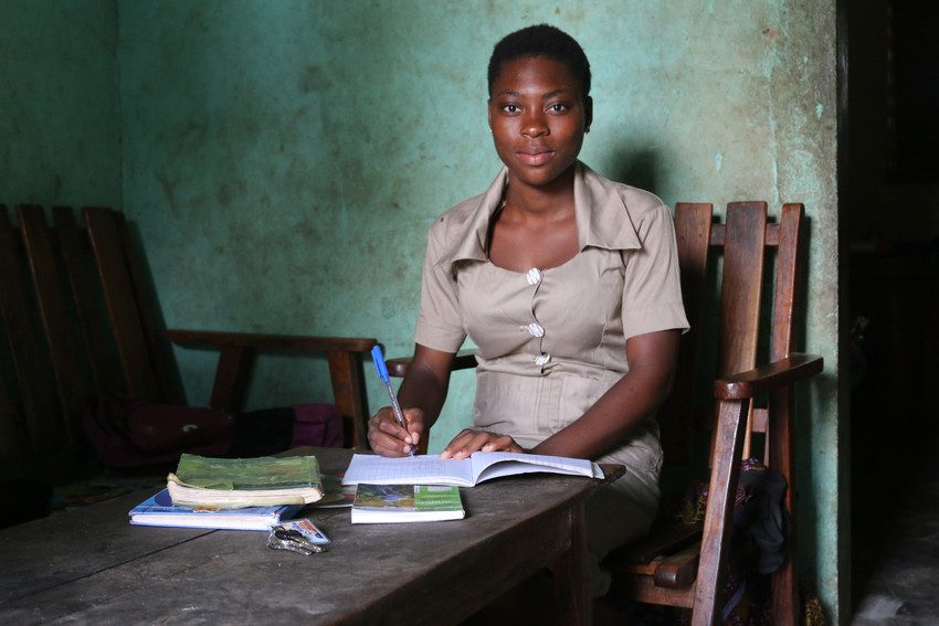 Véronique writing in her workbooks at her desk at school. 