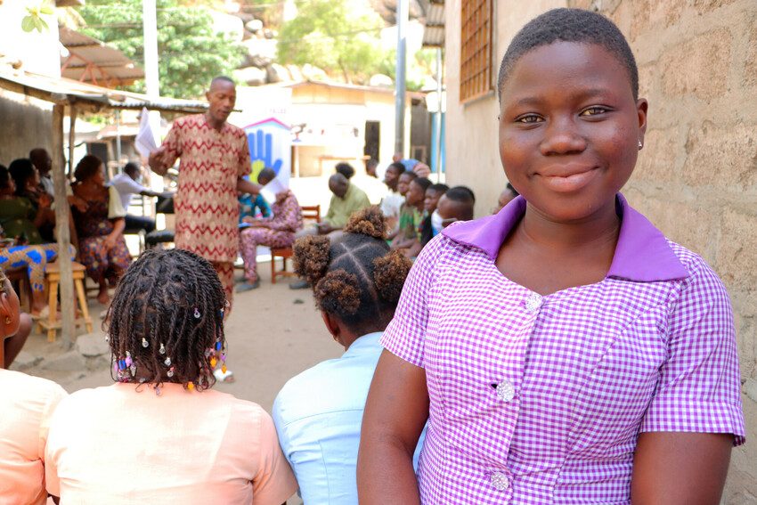 Majoie standing and smiling at the camera in front of the Plan for Girls talk participants.