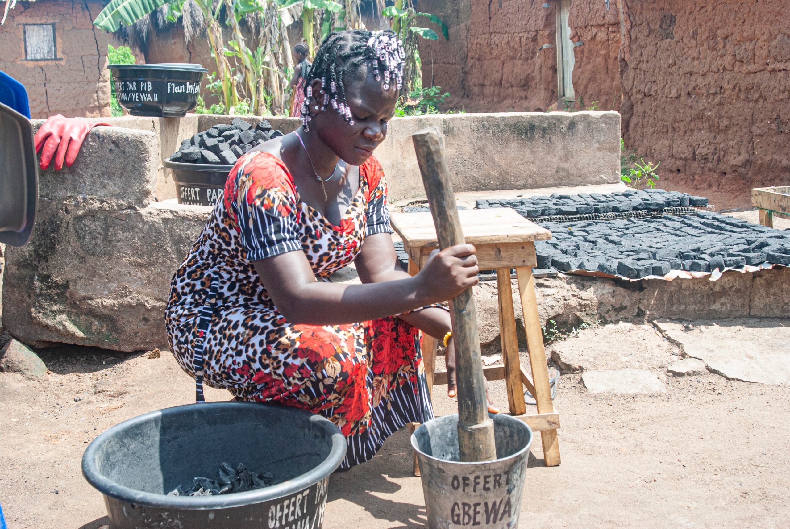 Sophie crushing palm nut shells to make a ecological charcoal