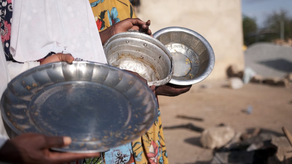 Displaced women holding empty bowls