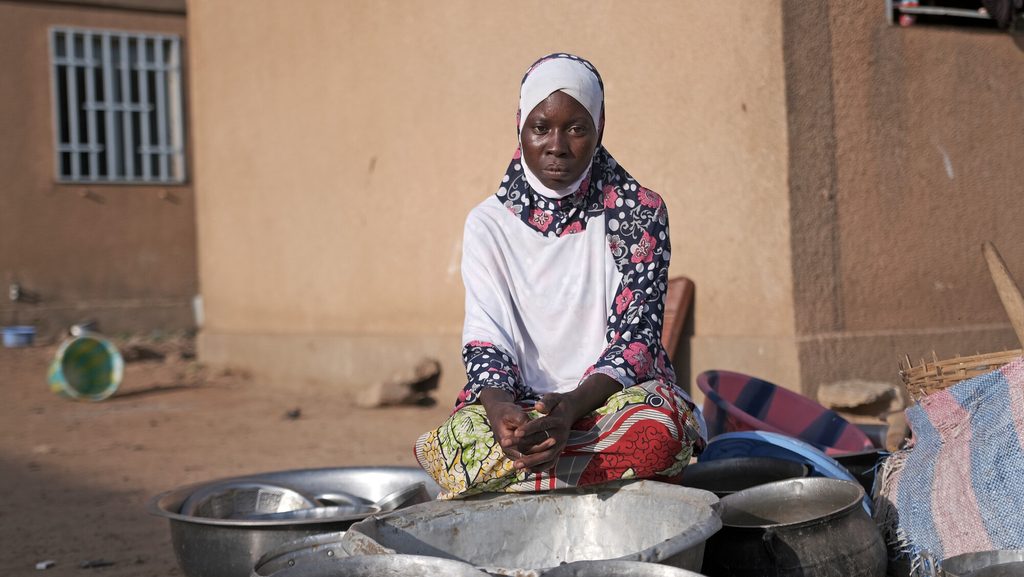 A displaced woman with empty bowls around her, unable to find food to cook