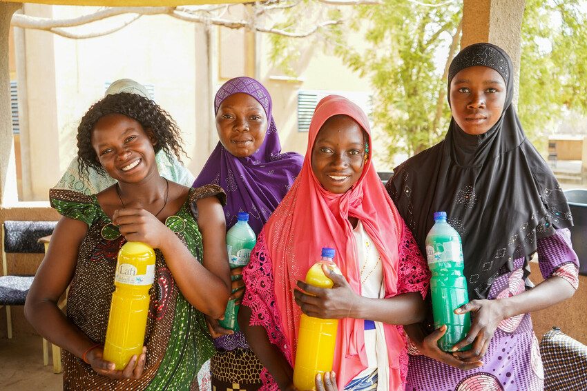 Bernadette with displaced girls and bottles of soap they made together