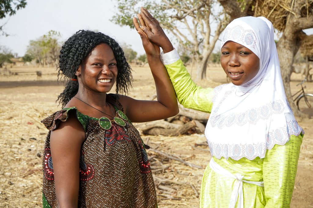 Bernadette (left) and her displaced friend Neima, both smiling and looking into the camera. 