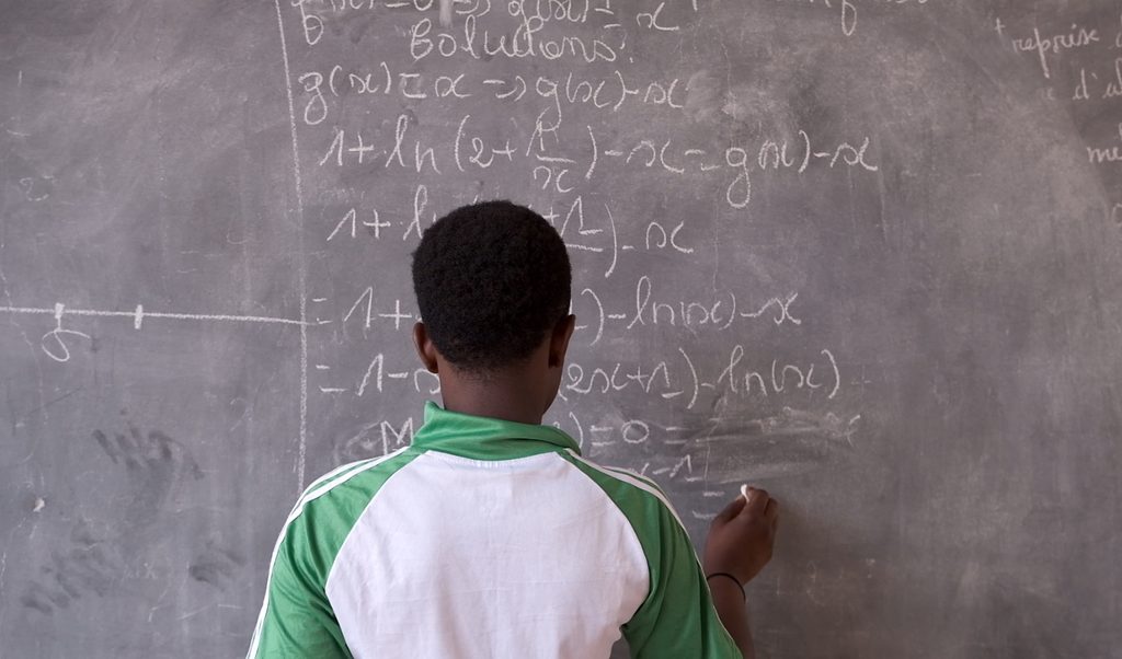 Absetou writing on a black board at school