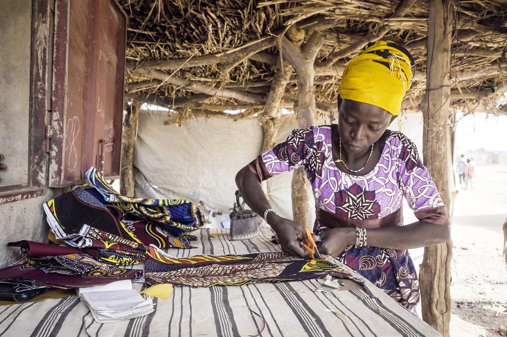 Bandiba cutting a piece of cloth in her sewing workshop