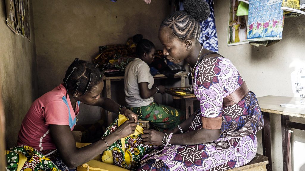 Bandiba and her apprentice working and looking at a piece of cloth