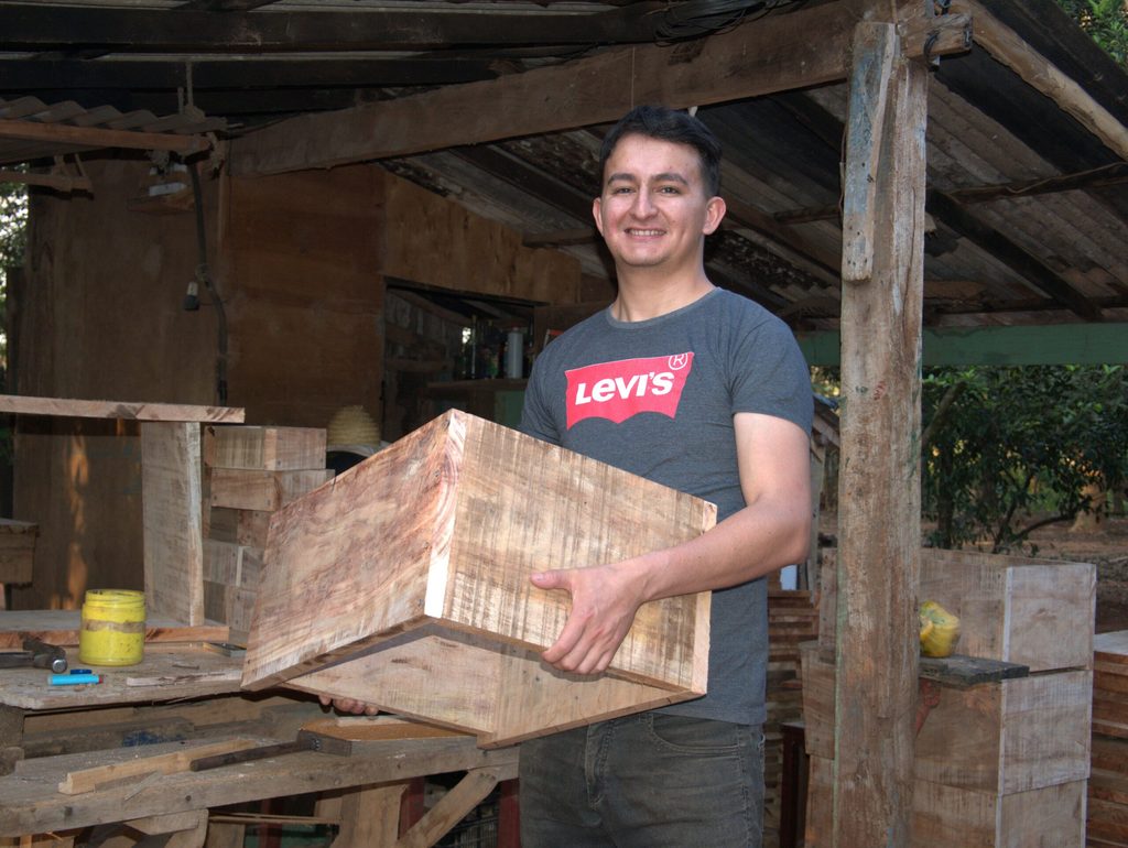 Delio, bee-keeping entrepreneur, holding a wooden box. 