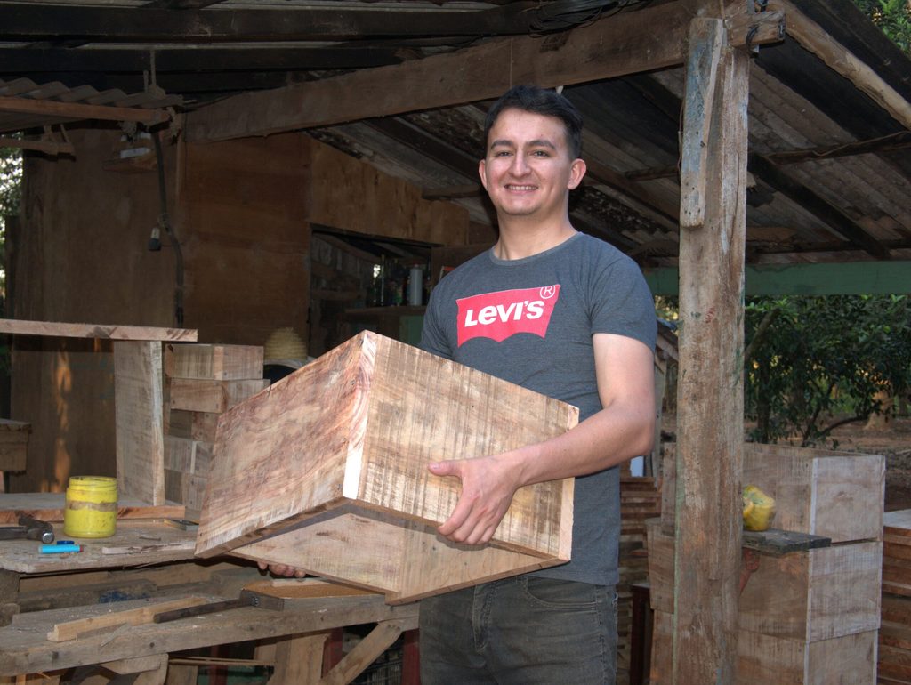 Delio, bee-keeping entrepreneur, holding a wooden box.