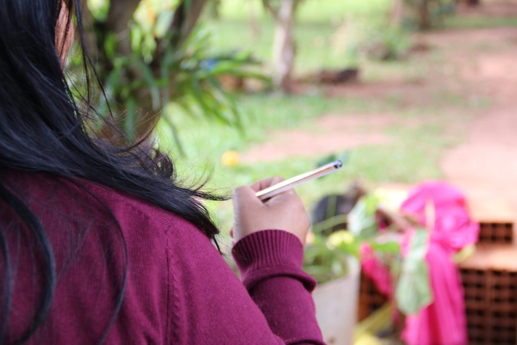 Ana facing away from a camera using a pencil. 