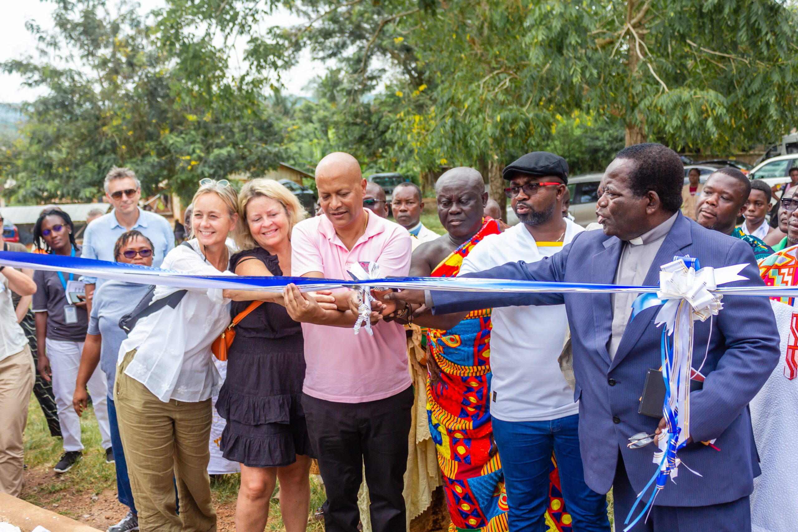 Plan International staff members and stakeholders cut a ribbon to open the new school building