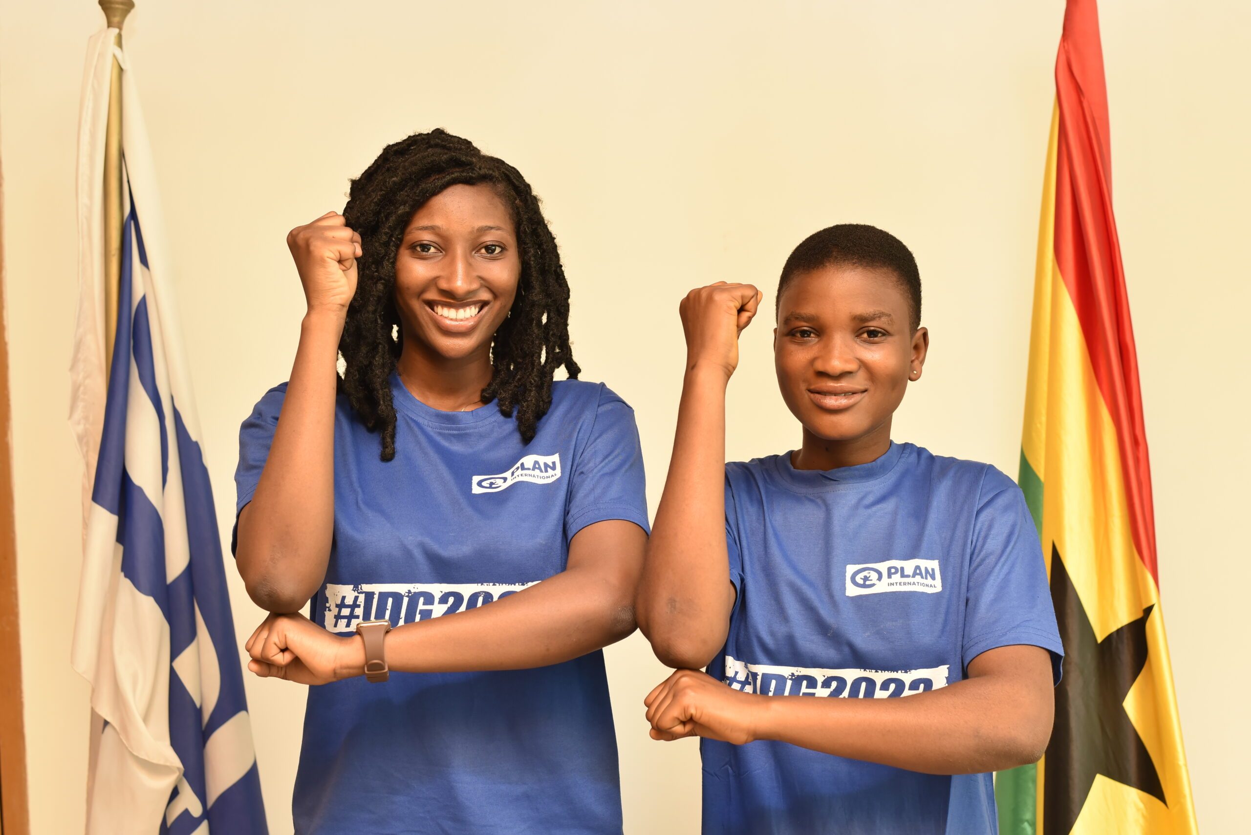 Linda and Mary standing side by side with arms in a L shape to signify girls' rights. 