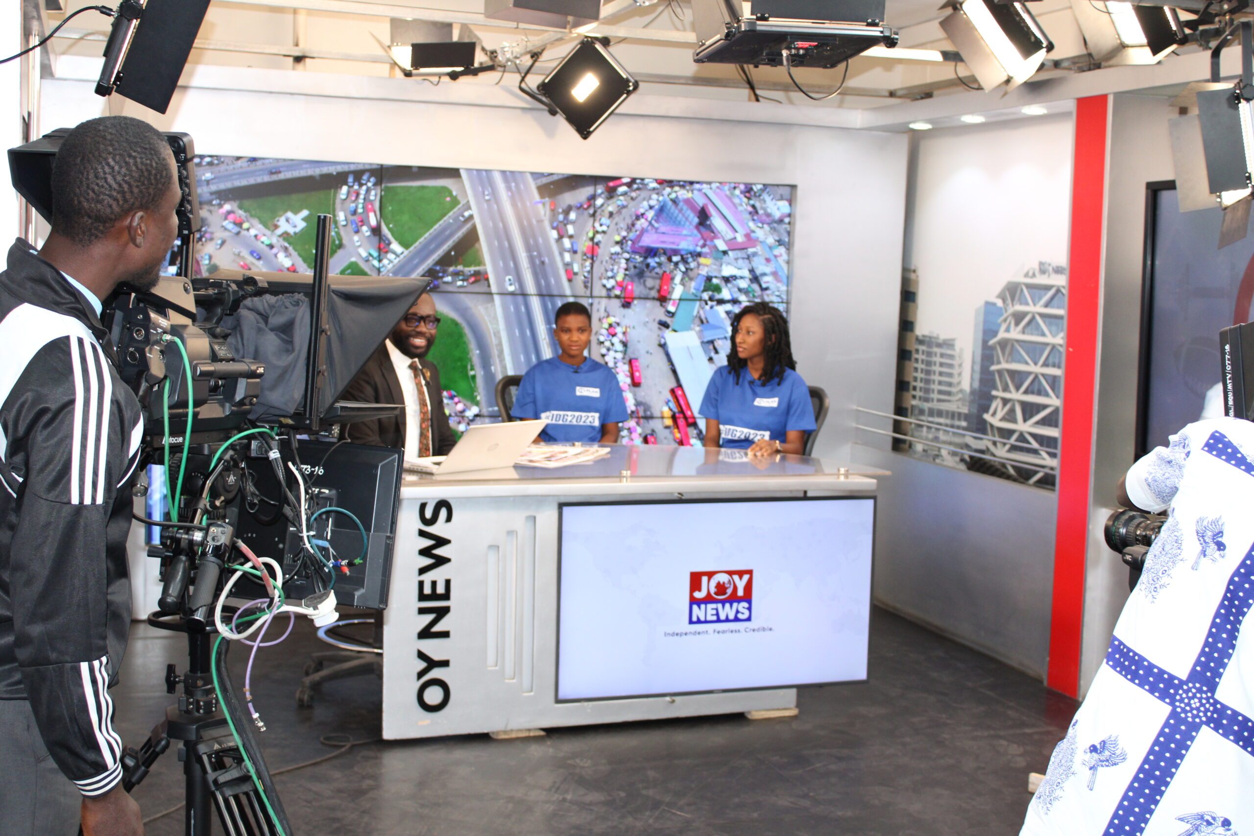 A male TV presenter sitting at a news desk with Linda and Mary. 