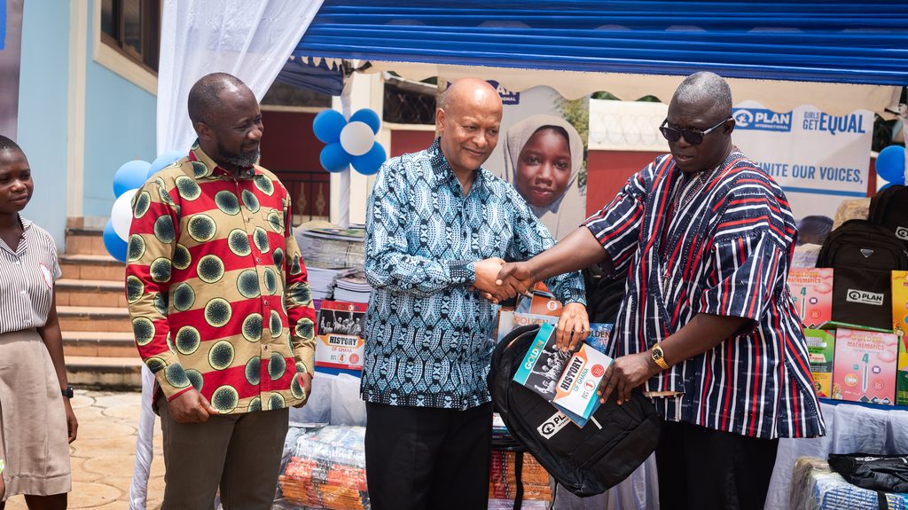 Country Director hands over schoolbag and books to a beneficiary community member.