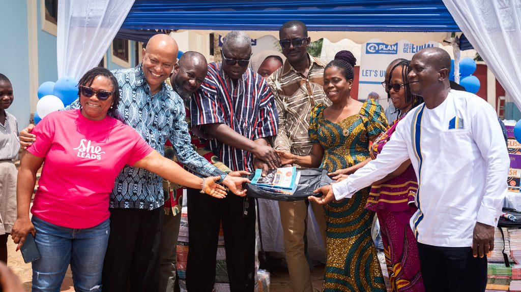 Plan International staff and learning material beneficiaries.