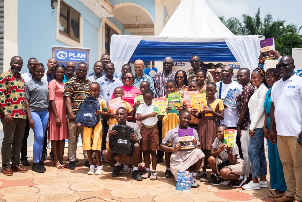 A group of people smiling for a photo at a learning material handover event. 