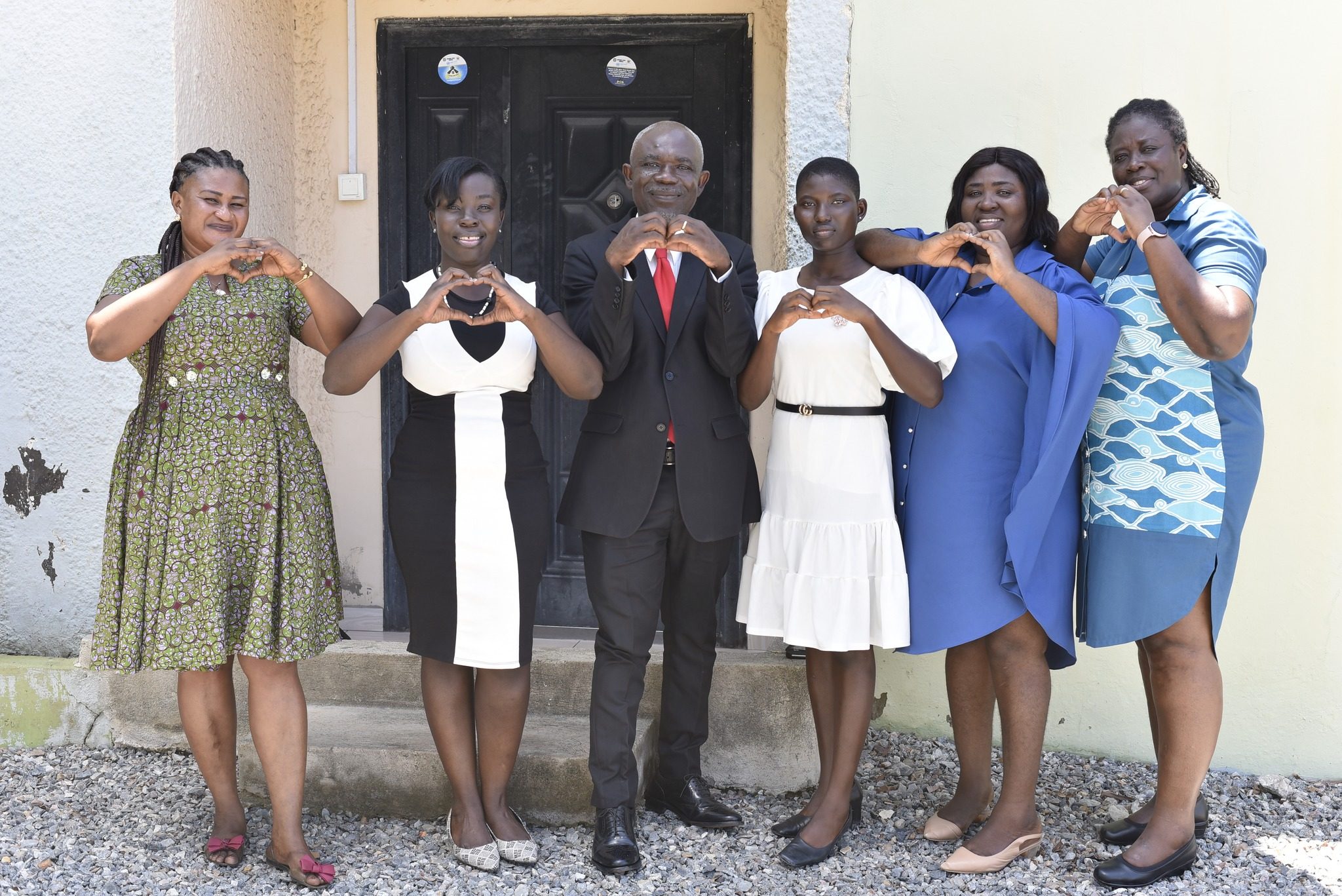 Sophia and others make heart symbols for peace. 