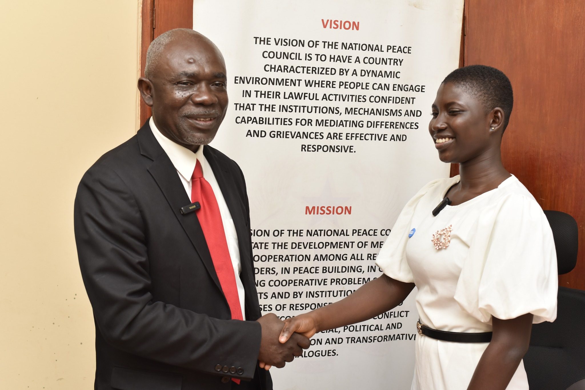 Sophia and the Board Chair of the National Peace Council shake hands.