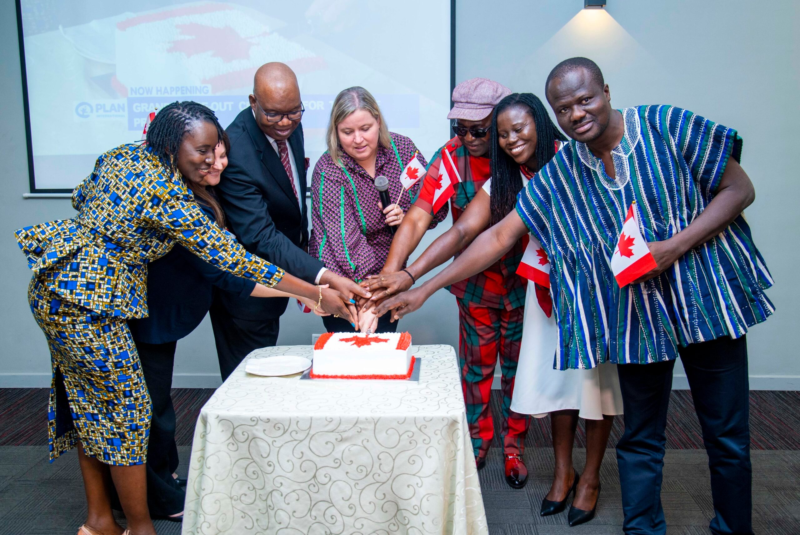 Group photo of people cutting a cake together. 