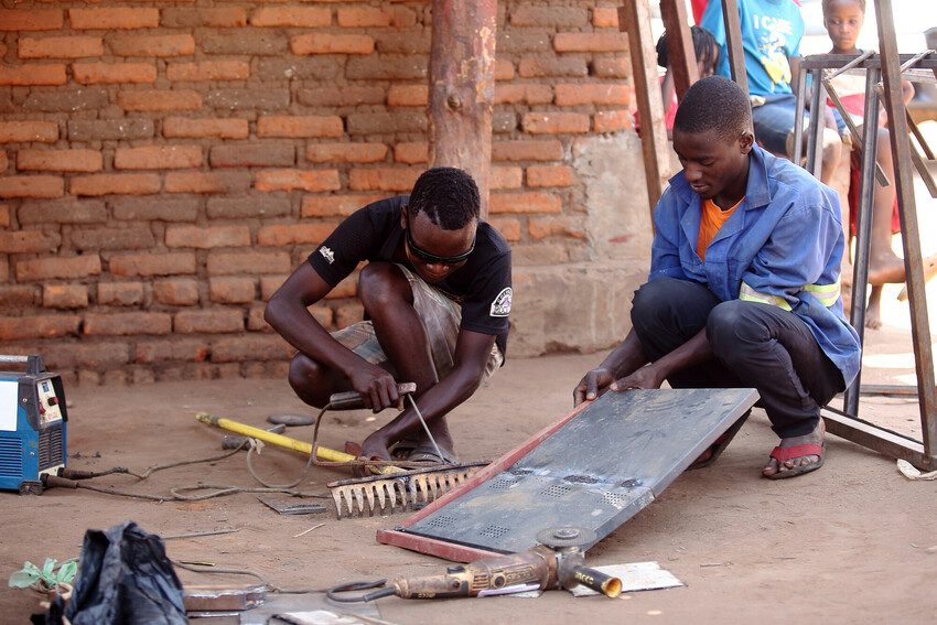 Cosmas and his employee working on some metal.