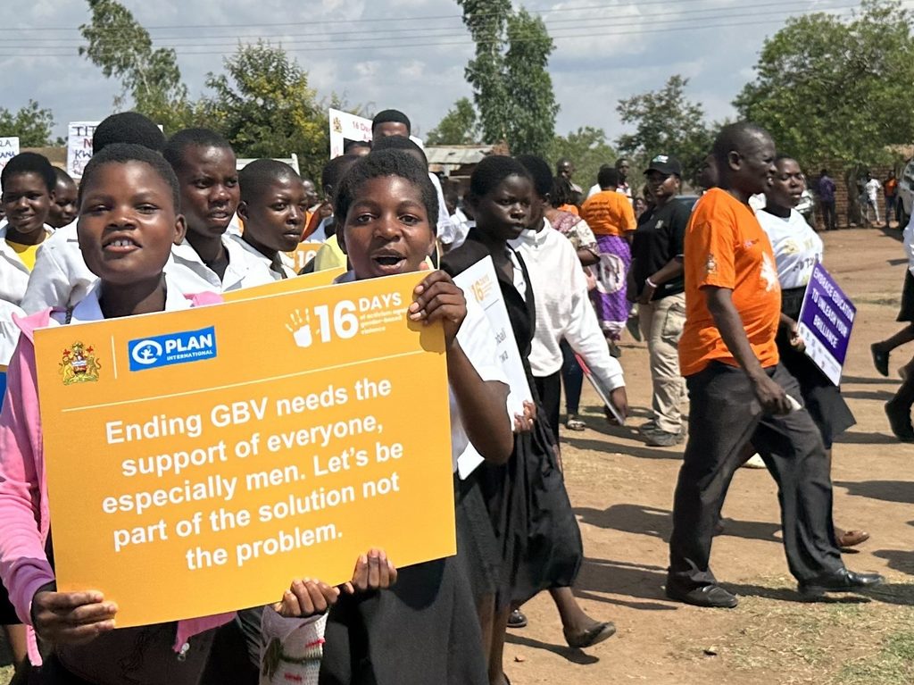 Young girls carry a message from Plan Malawi