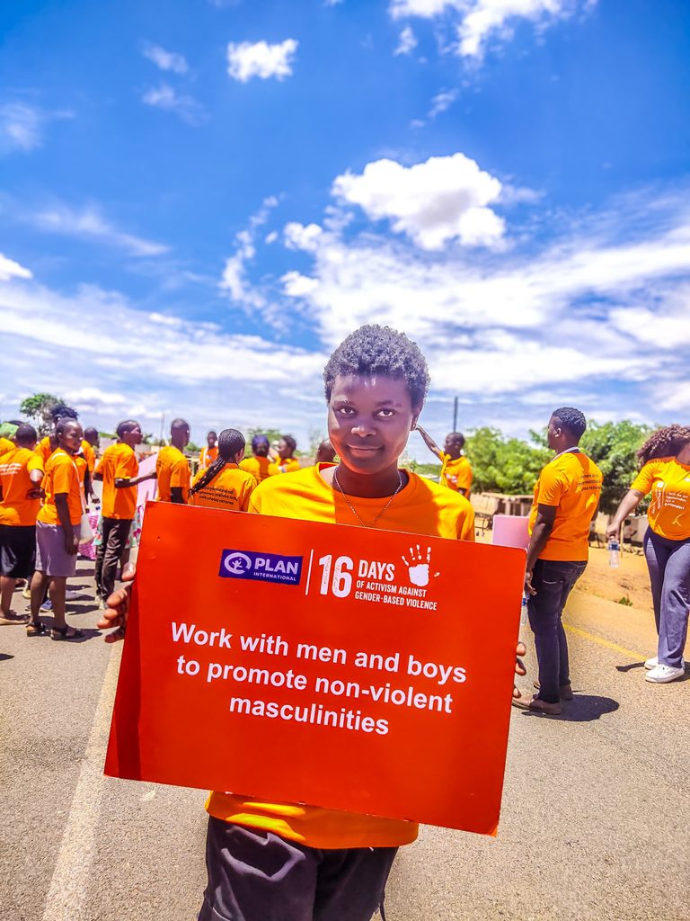 Girls holds up a sign calling for men and boys to be involved in ending gender-based violence.