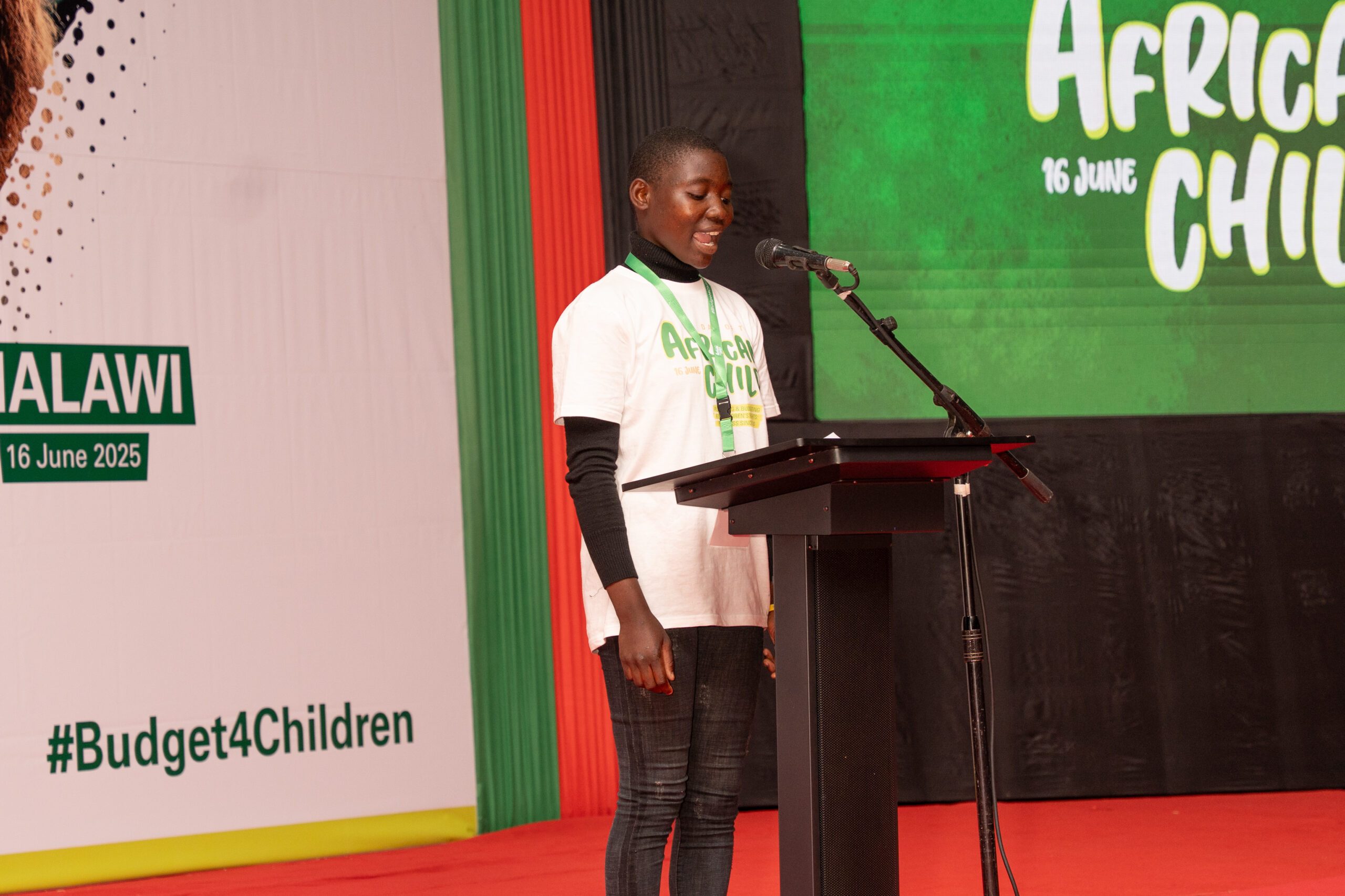 Loyce speaking into a microphone on stage at the event.