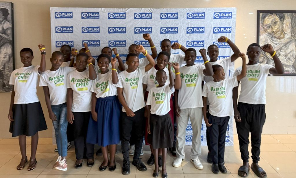 A group of children raise their arms.