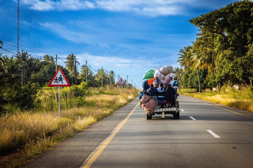 A truck piled high with possessions drives down an empty road.