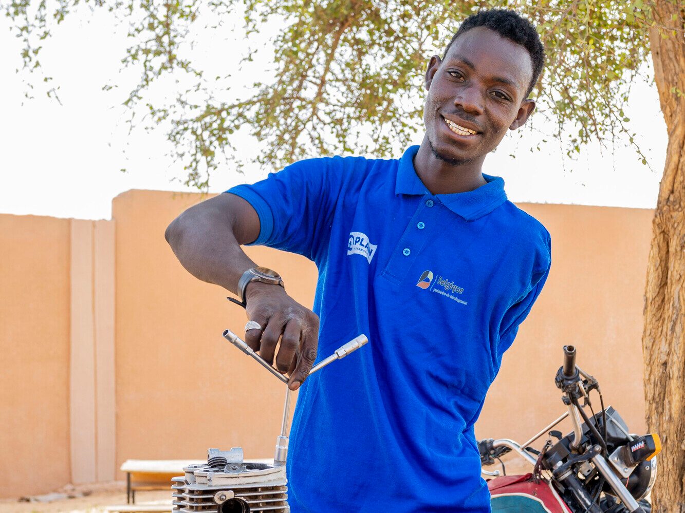 Lawali holding a tool used for repairing a motorcycle