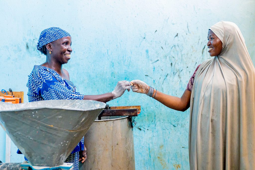 Sapa receives payment from a woman for use of the grinding machine that runs on solar energy in Maradi region, central Niger.