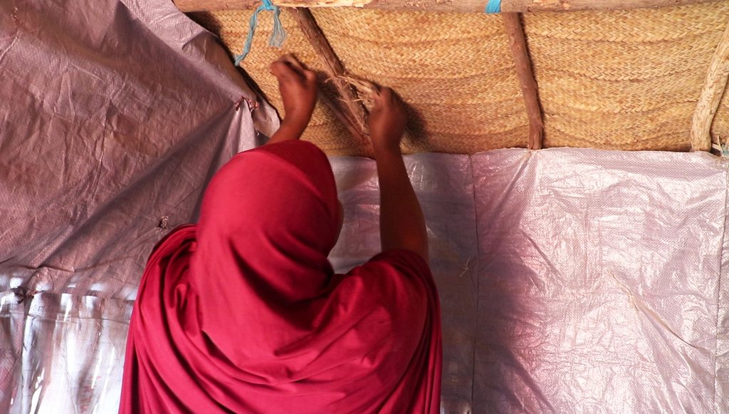 Yakoura fixing the roof of a tent in her home in Diffa region.