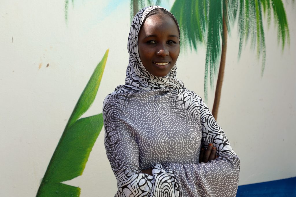 Youth leader Bintou poses proudly with folded arms. 