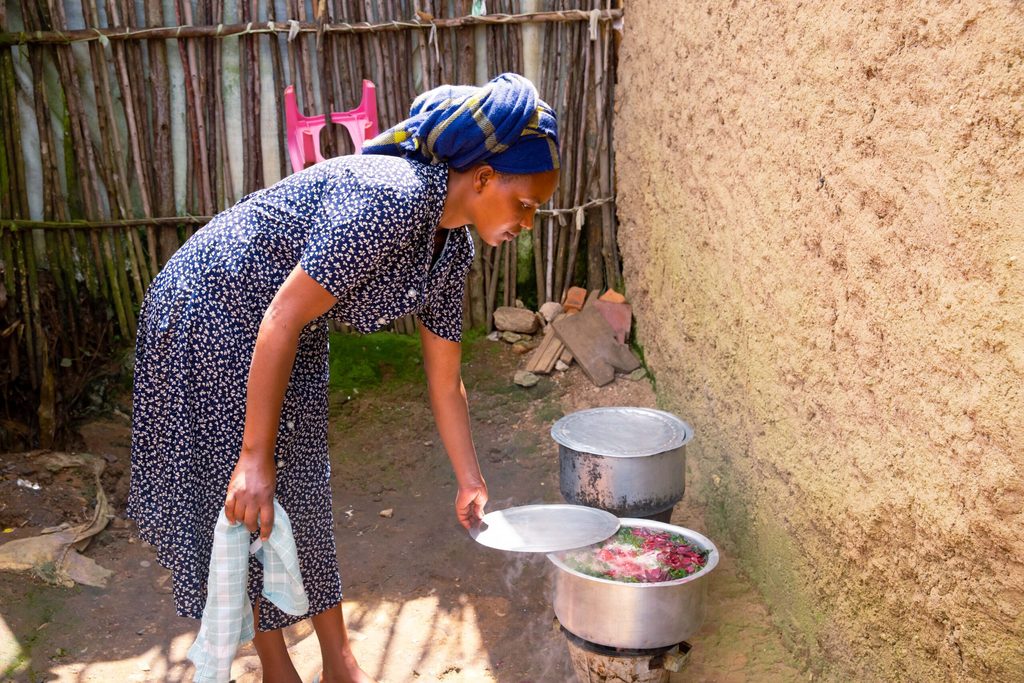 Aimerance checking on a pot of cooking food.