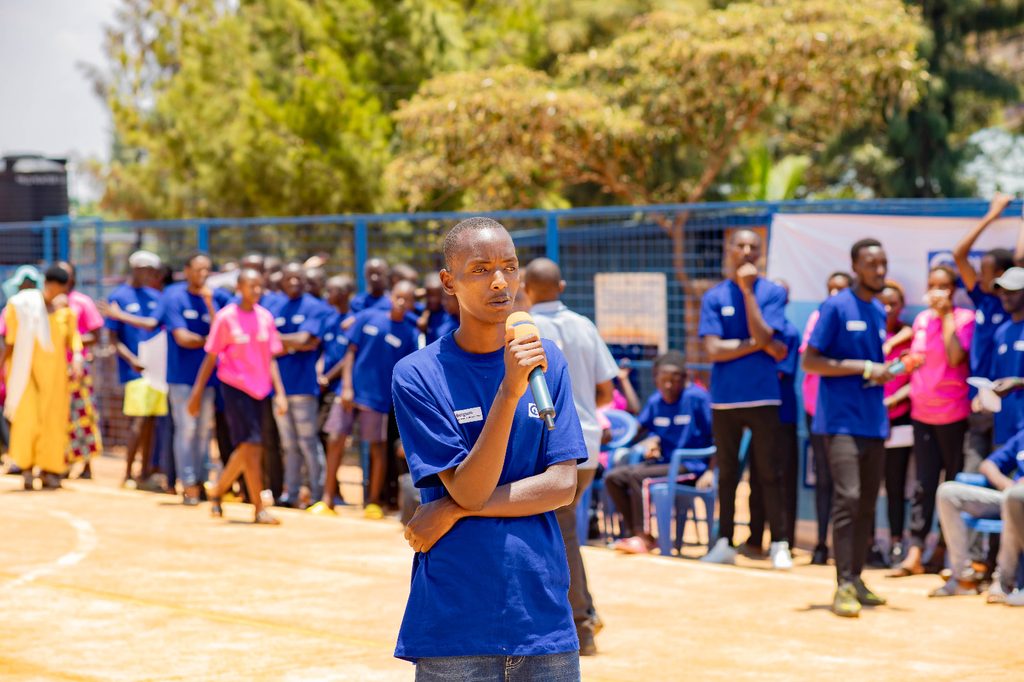 Merveille speaking at an event with a microphone.
