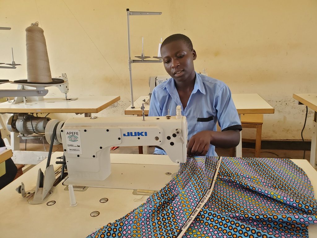 Claudine, a teen mother in working at a sewing machine.