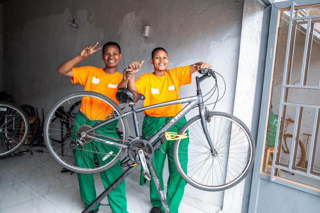 Olivia and Joyce pose behind a bike they are mending.