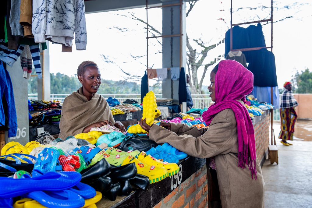 A refugee youth entrepreneur serves a client at the local market.