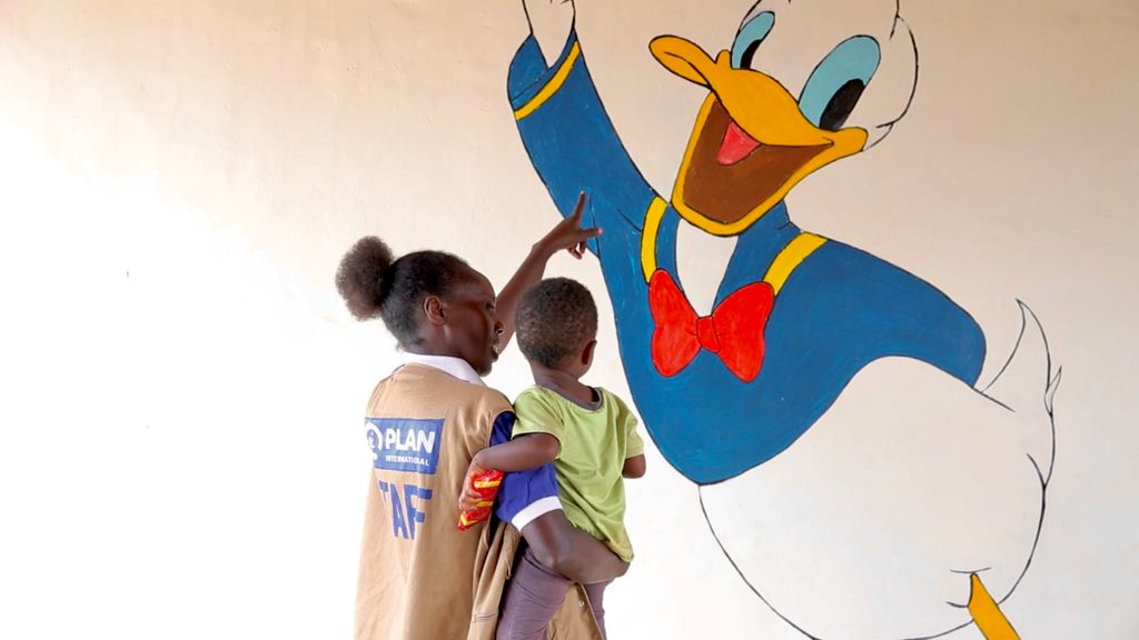 Christine holding a child in a safe space at the refugee camp.