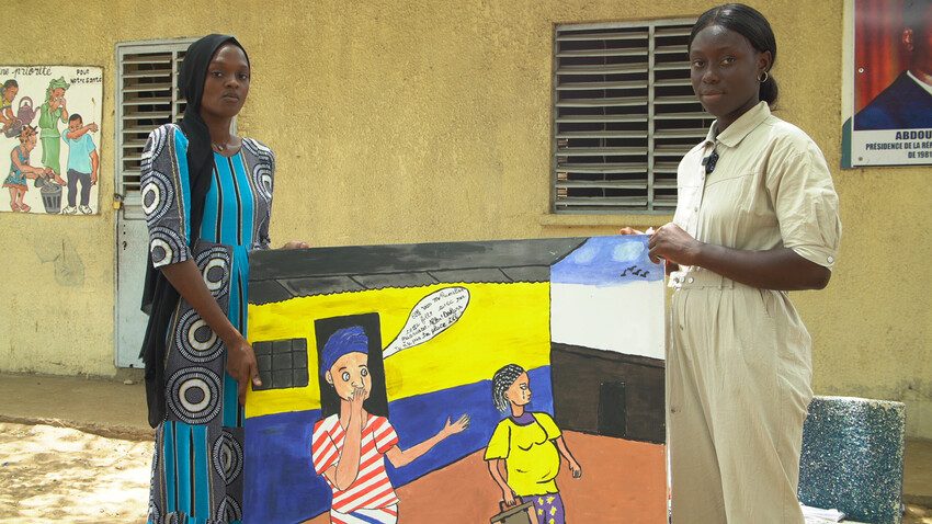 Fatoumata and another young woman holding one of her finished paintings.