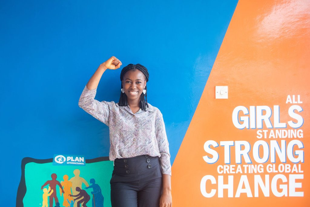 Lois in front of All Girls Standing Strong mural.